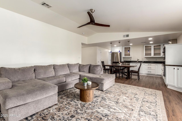 living room featuring lofted ceiling, ceiling fan, dark wood-style flooring, and visible vents