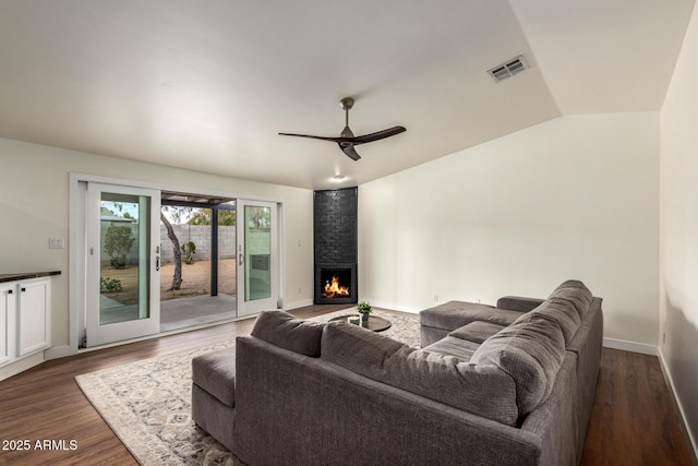 living room featuring a large fireplace, visible vents, a ceiling fan, lofted ceiling, and dark wood-style flooring