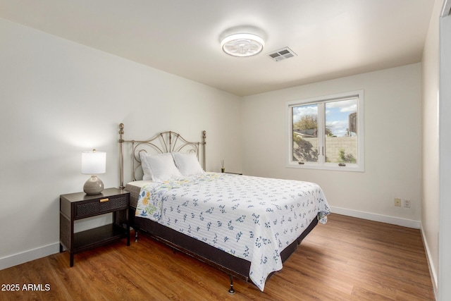 bedroom with wood finished floors, visible vents, and baseboards