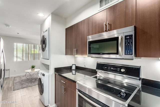 3635 N 68th St Unit 5, Scottsdale, AZ 85251 - kitchen with appliances with stainless steel finishes, estacked washer and dryer, wood tiled floors, dark countertops, and baseboards