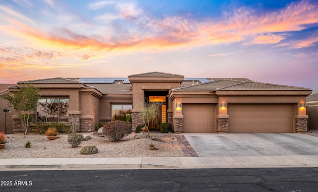 prairie-style house featuring a garage and solar panels