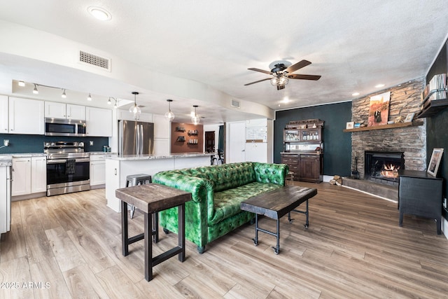 living room featuring a textured ceiling, light wood-type flooring, and a fireplace