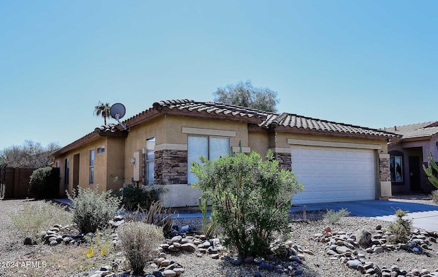 view of side of home featuring stucco siding, a garage, stone siding, driveway, and a tiled roof