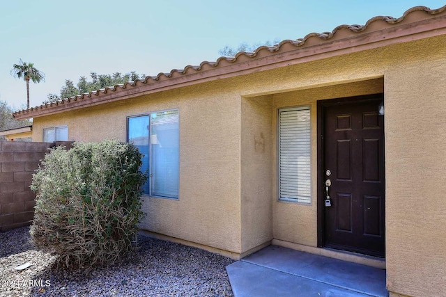 property entrance featuring fence and stucco siding