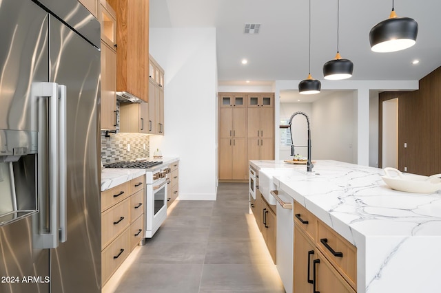 kitchen featuring light stone countertops, pendant lighting, high quality appliances, and a large island