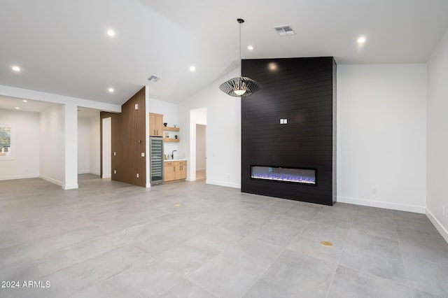 unfurnished living room with a large fireplace, sink, and high vaulted ceiling