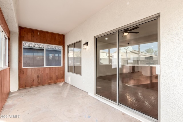 unfurnished sunroom featuring ceiling fan