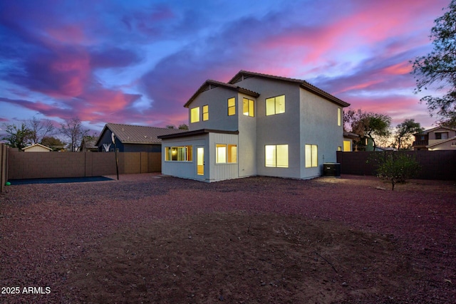 back house at dusk featuring central AC