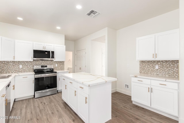 kitchen featuring light wood-type flooring, a kitchen island, white cabinets, and appliances with stainless steel finishes