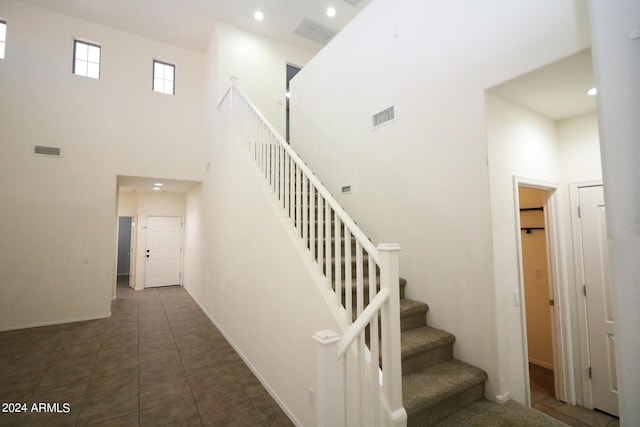 staircase featuring tile patterned floors and a high ceiling