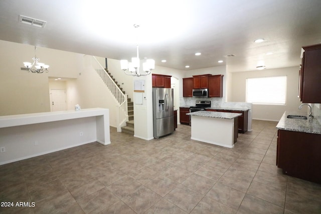 kitchen with appliances with stainless steel finishes, sink, an inviting chandelier, and decorative light fixtures