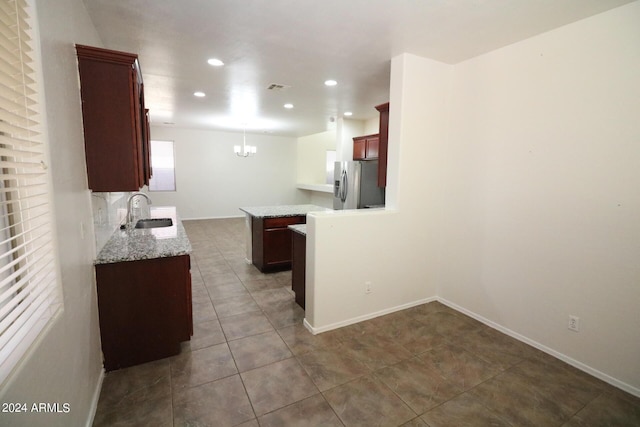 kitchen featuring sink, a center island, stainless steel fridge, dark tile patterned flooring, and pendant lighting