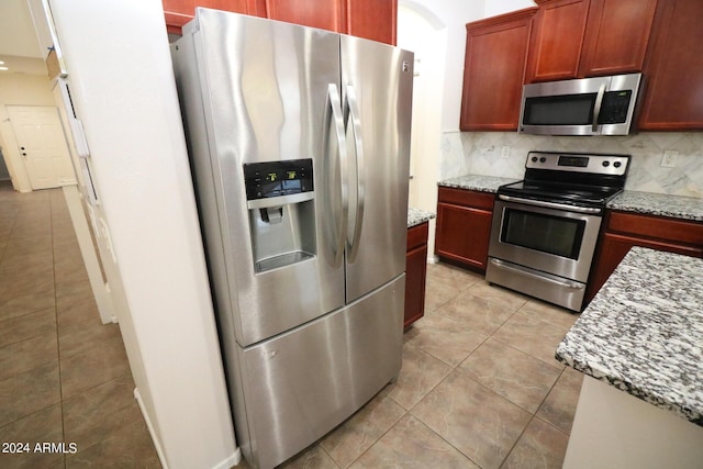 kitchen featuring light stone counters, stainless steel appliances, light tile patterned flooring, and tasteful backsplash