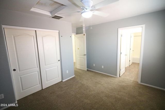 unfurnished bedroom featuring ceiling fan, a closet, and light carpet