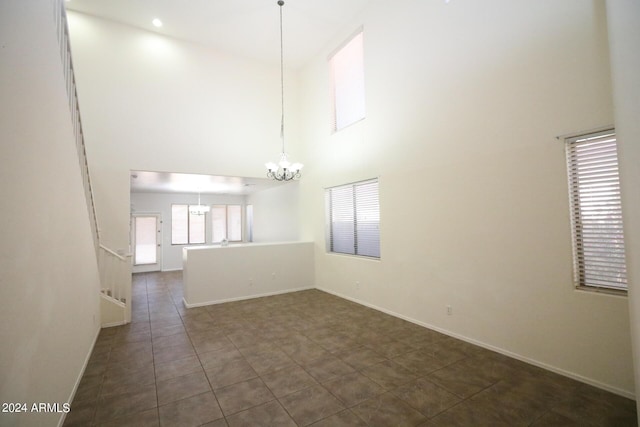 tiled spare room with a chandelier and a high ceiling