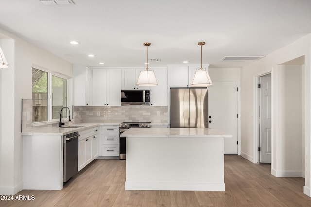 kitchen featuring sink, stainless steel appliances, light hardwood / wood-style flooring, pendant lighting, and a kitchen island