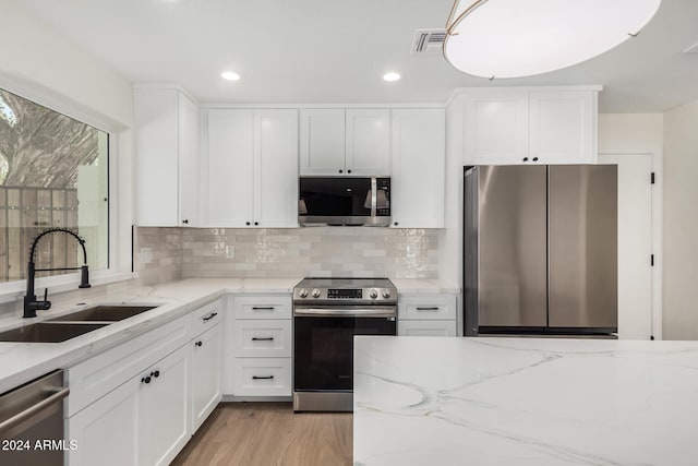 kitchen with white cabinets, light stone counters, sink, and appliances with stainless steel finishes