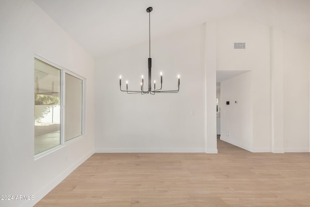 unfurnished dining area featuring a chandelier, lofted ceiling, and light hardwood / wood-style flooring