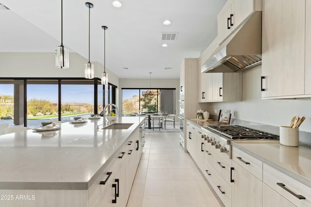 kitchen featuring sink, stainless steel gas cooktop, pendant lighting, a spacious island, and light tile patterned flooring