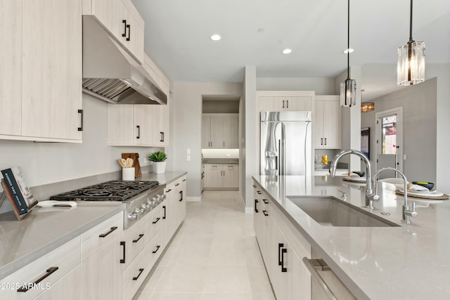 kitchen featuring sink, light stone countertops, light tile patterned floors, decorative light fixtures, and stainless steel appliances