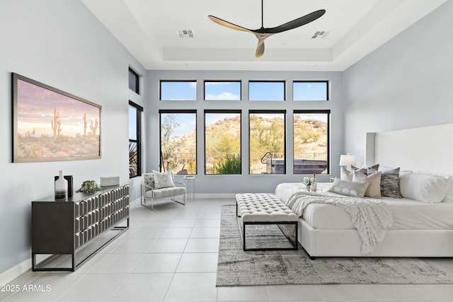 bedroom with ceiling fan, a raised ceiling, and light tile patterned floors