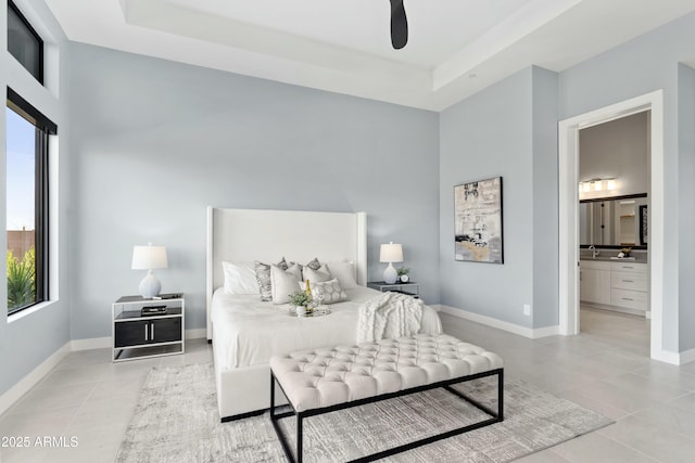 bedroom with a raised ceiling, ensuite bath, ceiling fan, and sink