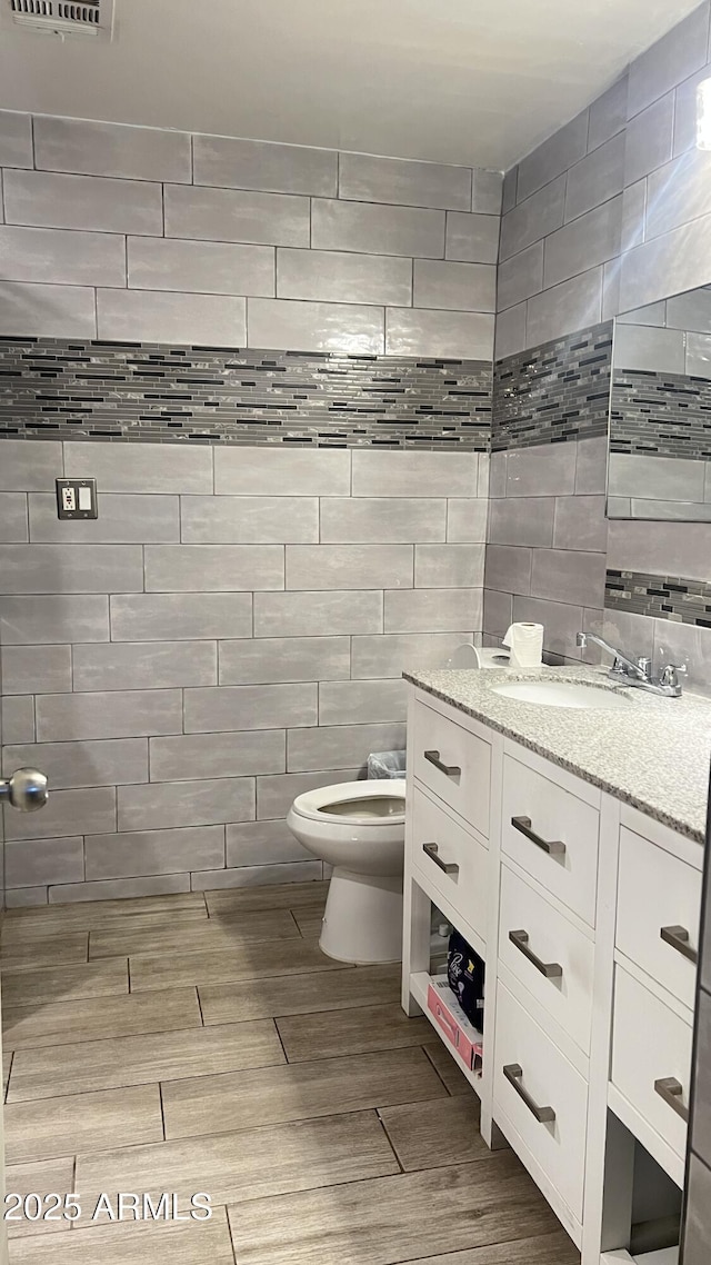 bathroom with vanity, wood-type flooring, tile walls, and toilet