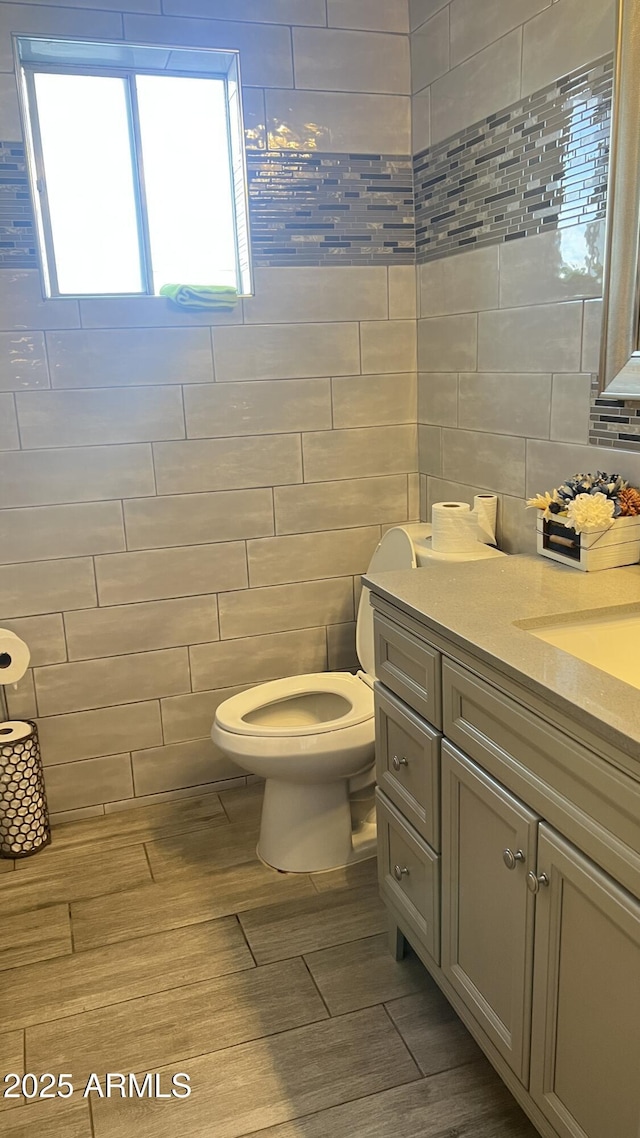 bathroom with vanity, tile walls, and toilet