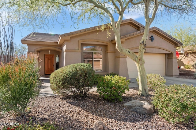 mediterranean / spanish-style home featuring driveway, an attached garage, a tile roof, and stucco siding