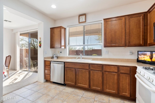 kitchen featuring brown cabinets, a sink, light countertops, white gas stove, and stainless steel dishwasher