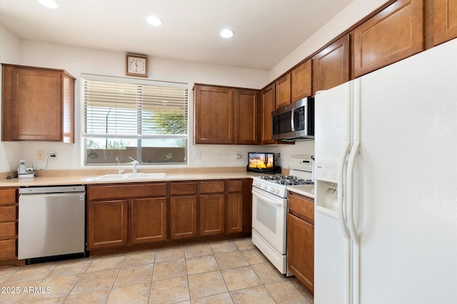 kitchen with brown cabinetry, stainless steel appliances, a sink, and light countertops