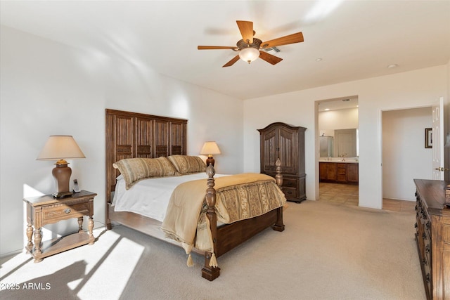 bedroom with a ceiling fan, connected bathroom, and light colored carpet