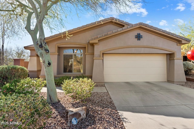 mediterranean / spanish-style home featuring an attached garage, a tile roof, concrete driveway, and stucco siding