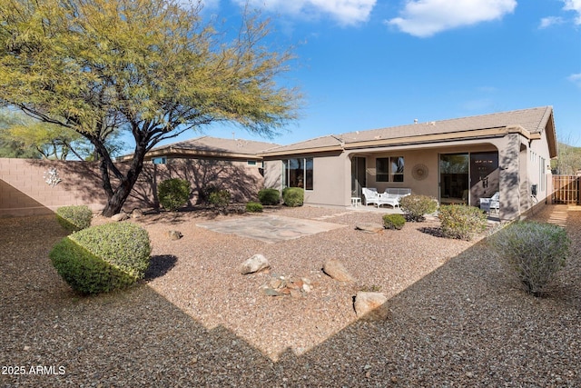 rear view of property featuring stucco siding, a fenced backyard, and a patio