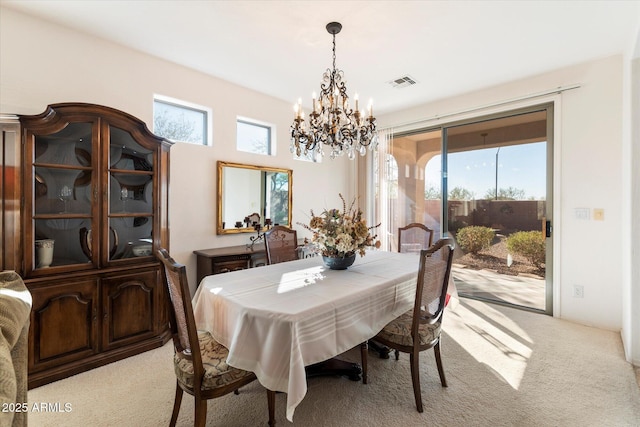 dining room with light colored carpet, visible vents, plenty of natural light, and a notable chandelier