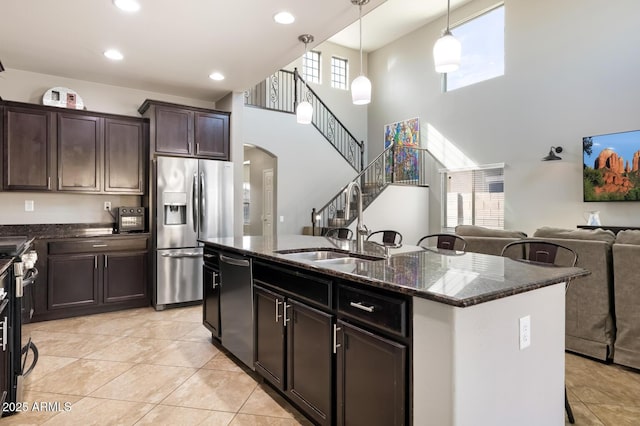 10840 W Saddlehorn Rd, Peoria, AZ 85383 - kitchen with pendant lighting, a kitchen island with sink, dark brown cabinets, stainless steel appliances, and dark stone counters