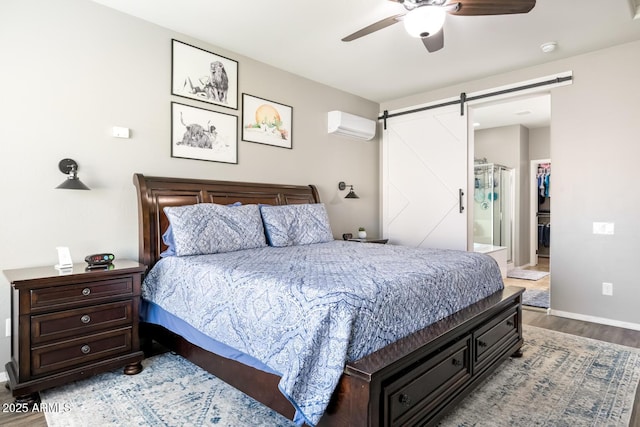 10840 W Saddlehorn Rd, Peoria, AZ 85383 - bedroom featuring a walk in closet, a wall mounted AC, hardwood / wood-style flooring, ceiling fan, and a barn door