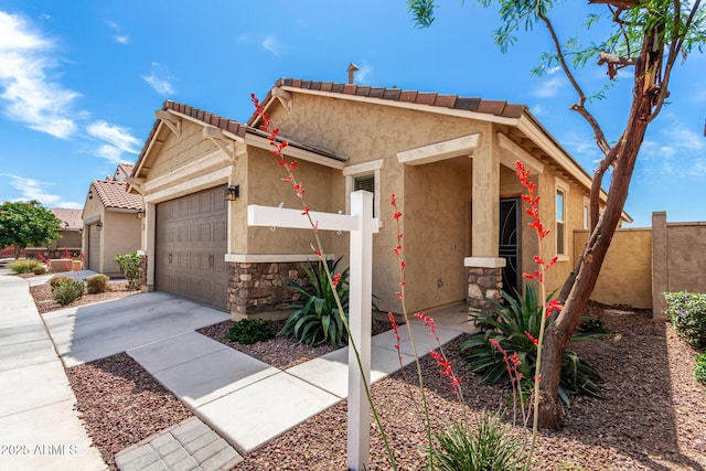 14355 W Valentine St, Surprise, AZ 85379 - view of front facade with fence, stone siding, stucco siding, an attached garage, and driveway