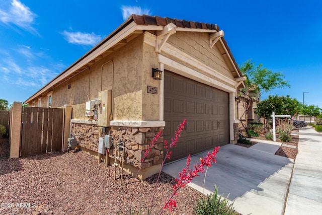 14355 W Valentine St, Surprise, AZ 85379 - view of home's exterior featuring fence, an attached garage, stone siding, stucco siding, and concrete driveway