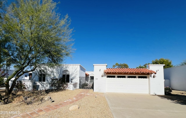 mediterranean / spanish house featuring a garage, fence, driveway, a tiled roof, and stucco siding