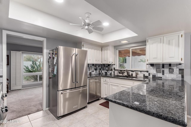 kitchen with stainless steel appliances, a raised ceiling, decorative backsplash, white cabinetry, and a sink