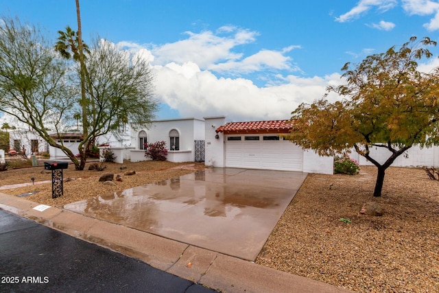 view of front of property with a garage, driveway, a tiled roof, and stucco siding