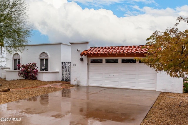 mediterranean / spanish-style house with a garage, concrete driveway, a tiled roof, and stucco siding