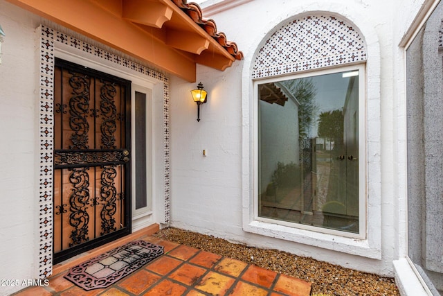 entrance to property featuring a tile roof and stucco siding