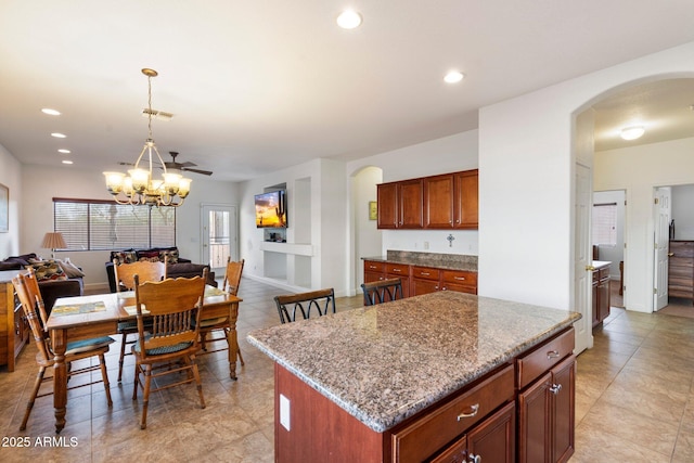 kitchen with light stone counters, a center island, a chandelier, and decorative light fixtures