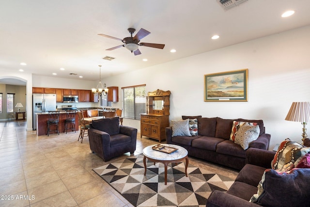 tiled living room featuring ceiling fan with notable chandelier