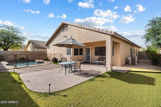 rear view of house with a lawn, a fenced in pool, a patio, and central AC