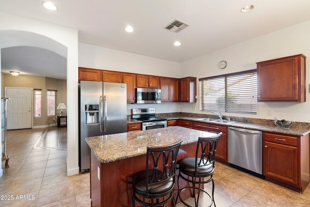 kitchen featuring sink, a kitchen island, light tile patterned floors, and appliances with stainless steel finishes