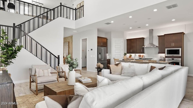 living room featuring a towering ceiling and light wood-type flooring