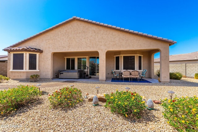 back of property featuring a patio and a hot tub